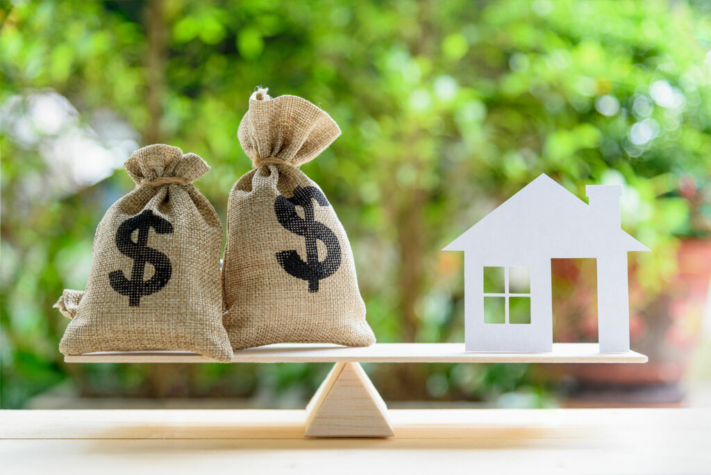 Balancing money sacks against a home.